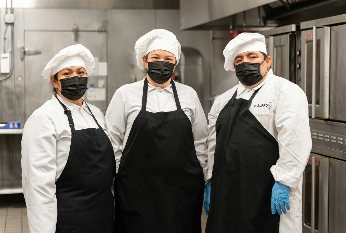 Personal de cocina con chaquetillas blancas y delantales de trabajo limpios